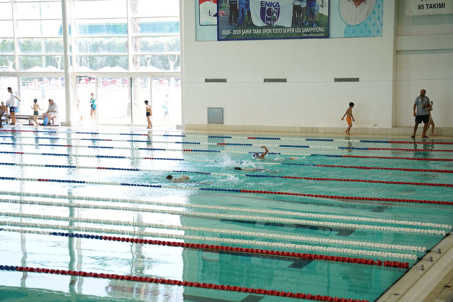 Foto ilustrativa: crianças praticando natação em piscina com raias